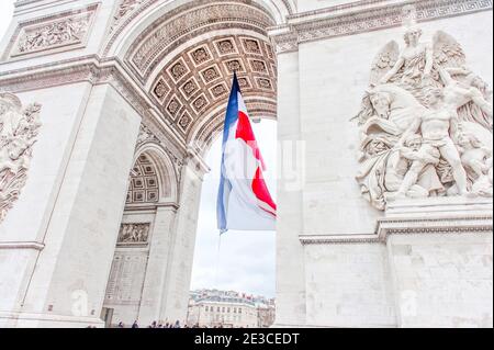 Bandiera francese sventolando nel vento all'Arco di Trionfo, Parigi Foto Stock