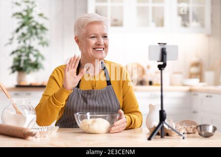 Blogger alimentare donna anziana che registra la sua cucina da in cucina Foto Stock