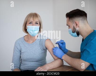 Vaccinazione del coronavirus per gli anziani. Donna matura che viene immunizzata contro covid-19 in clinica durante la sua visita al medico Foto Stock