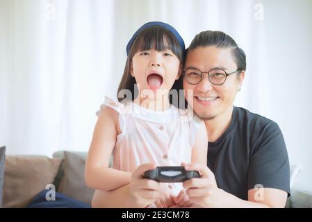 Asian Padre e cute figlia godere e giocare gioco di console in vacanza a casa Foto Stock