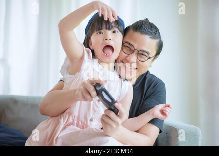 Asian Padre e cute figlia godere e giocare gioco di console in vacanza a casa Foto Stock