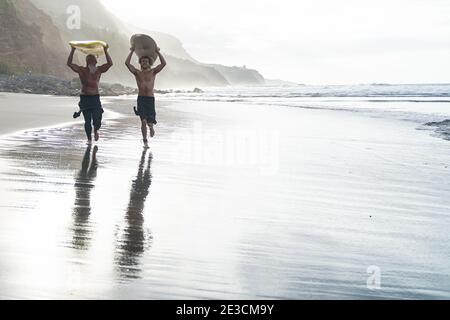 Padre e figlio fanno surf in una giornata perfetta. Amici che escono nell'oceano. Stile di vita sportivo e concetto di sport estremo. Foto Stock