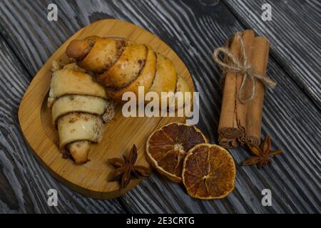 Cannella e ciambelle di semi di papavero. Pasticcini ricchi. Nelle vicinanze ci sono bastoncini di cannella, anice e arance secche. Primo piano. Foto Stock