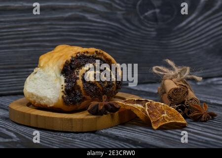 Cannella e ciambelle di semi di papavero. Pasticcini ricchi. Nelle vicinanze ci sono bastoncini di cannella, anice e arance secche. Primo piano. Foto Stock