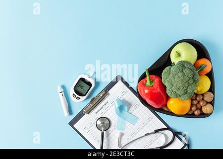 Verdure fresche e frutta con glucometro vista dall'alto su sfondo blu. Concetto di dieta diabetica. Foto Stock