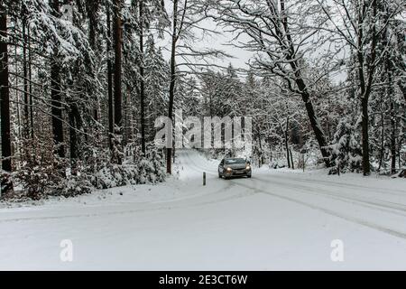 Auto su un pericoloso tratto di strada coperto di neve E Ice.Snowy strada attraverso Forest.Winter panorama.Driving in ghiacciato paesaggio.Bad con Foto Stock