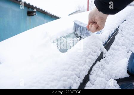 Rimuovere la neve dal parabrezza della vettura con la spazzola per auto Foto Stock