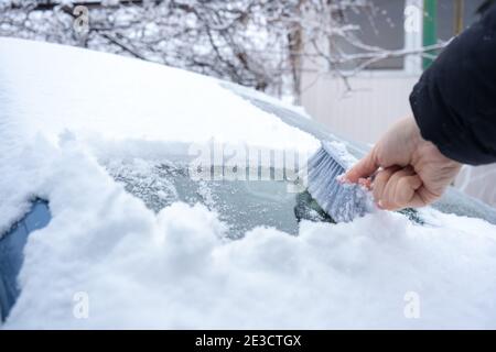 Rimuovere la neve dal parabrezza della vettura con la spazzola per auto Foto Stock