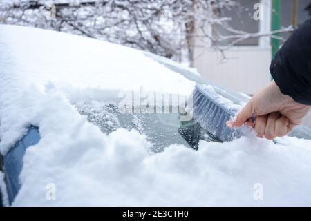 Rimuovere la neve dal parabrezza della vettura con la spazzola per auto Foto Stock