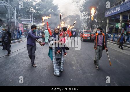 Kolkata, India. 18 gennaio 2021. Una donna che marciava per le strade mentre trasportava il suo bambino e una torcia durante la protesta. Diverse organizzazioni femminili come l'AIDWA (All India Democratic Women's Association), l'AIPWA (All India Progressive Women's Association) e l'AIKSCC (All India Kissan Sangharsh Coordination Committee) hanno organizzato proteste e hanno marciato in tutto il paese prima del giorno della Repubblica di quest'anno, Esprimere solidarietà con la protesta degli agricoltori contro il governo indiano ha imposto nuove leggi agricole al confine con il Singhu, Delhi. Credit: SOPA Images Limited/Alamy Live News Foto Stock