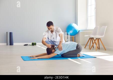 Chiropractor autorizzato o fisioterapista che aiuta la donna a fare l'esercitazione medica su tappetino sportivo Foto Stock