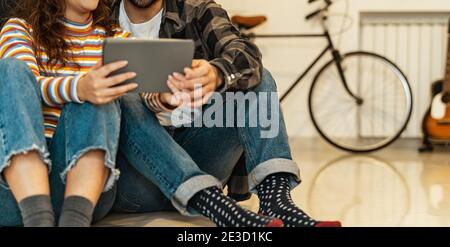 Giovane coppia che usa il tablet a casa - persone sociali che hanno Divertitevi con i nuovi dispositivi tecnologici di tendenza: Tecnologia e relazione concetto Foto Stock