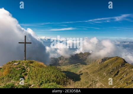 Italia Trentino - Sentiero della Pace in Val di Concei, cima e croce sommitale del Monte Cadria. Dalla cima si può godere un panorama a 360 gradi sulla montagna più alta delle Alpi Ledro: Sotto nel bacino della Malga Cadria. PERCORSO SAT 423. Foto Stock