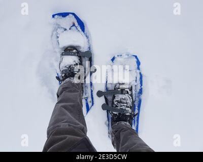 Vista dall'alto di una persona che indossa le racchette da neve invernali nella neve Foto Stock