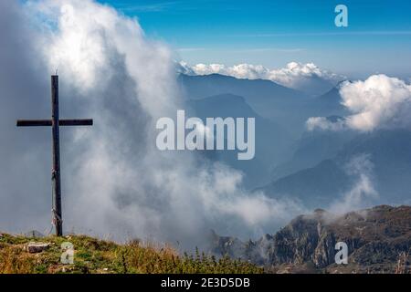 Italia Trentino - Sentiero della Pace in Val di Concei, cima e croce sommitale del Monte Cadria. Dalla cima si può godere un panorama a 360 gradi sulla montagna più alta delle Alpi Ledro: Sotto nel bacino della Malga Cadria. PERCORSO SAT 423. Foto Stock