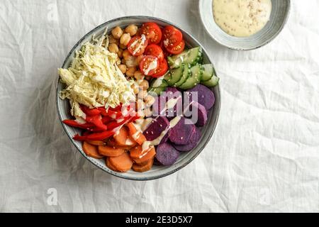 ciotola budha con batata viola, peperoni, cavolo, patate dolci, ceci, cetrioli sulla tovaglia di lino bianco Foto Stock