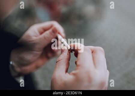 Vista dall'alto dell'uomo che fa una sigaretta fatta a mano in carta con tabacco marrone all'aperto. Spazio di copia Foto Stock