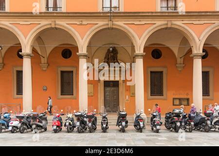 Una fila di scooter o motociclette parcheggiate all'esterno Un edificio storico nella città italiana di Bologna Foto Stock