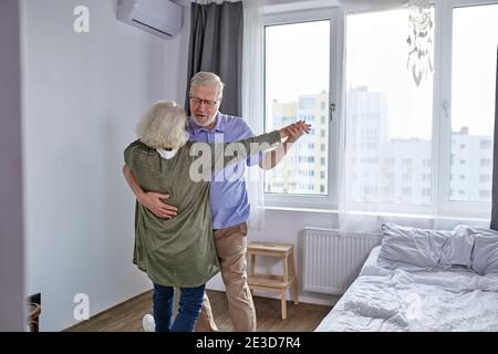 la coppia anziana ha divertimento ballare a casa, l'uomo e la donna maturo romantico capelli grigi si sentono energici attivi godersi il fine settimana di pensionamento della famiglia, trascorrere le vacanze Foto Stock