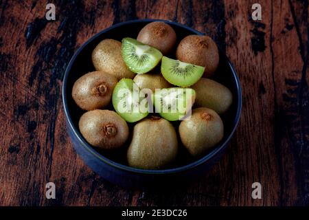 kiwi in un piatto di ceramica blu su un vecchio legno tabella Foto Stock