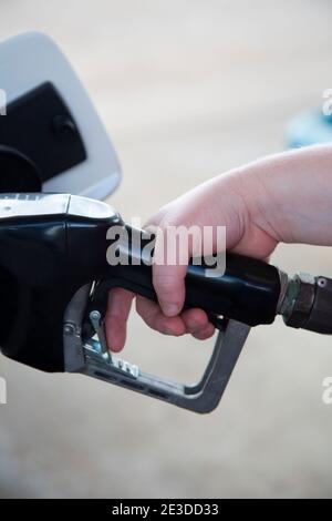 Mano della donna che spinge un manico generico della pompa del gas Foto Stock