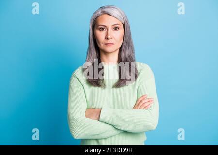 Foto di anziana signora pensionato incrociato armi serio sguardo macchina fotografica indossare un pullover verde isolato sfondo blu Foto Stock