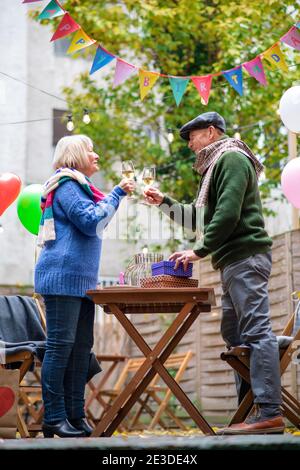 Felice coppia senior con vino in un caffè all'aperto in città, festeggiando il compleanno. Foto Stock