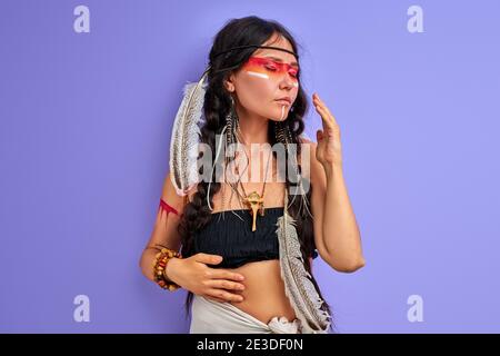 Shamanic femmina con piuma indiana su capelli e colorato make-up dipinto, ritratto in studio. etnia indiana Foto Stock