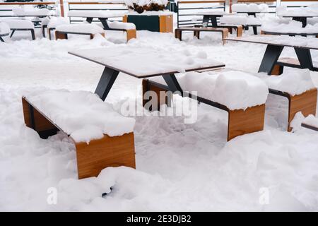 Tavoli e panche di caffè all'aperto, coperti di neve. Foto Stock