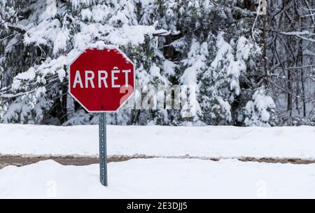 Un cartello Stop Road in francese (arrêt) durante la stagione invernale in Québec, Canada Foto Stock