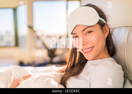 Donna asiatica felice svegliarsi la mattina presto dal sonno di bellezza che indossa la maschera di sonno dell'occhio per un buon riposo notturno. Sming giovane ragazza a letto Foto Stock