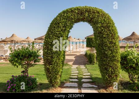 Ingresso attraverso un cancello verde con un sentiero in pietra che conduce alla spiaggia sabbiosa di Hurghada, Egitto. Foto Stock