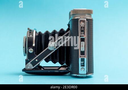 Vecchia fotocamera retrò vista da un lato contro il pastello blu mostrando nostalgia sensazione. Foto Stock