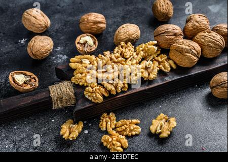 Nocciole sgusciate su tagliere di legno. Sfondo nero. Vista dall'alto Foto Stock