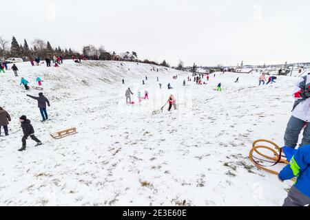 Bambini e adulti che slittano sul sito dell'antico Anfiteatro in inverno a Becsi-domb, Sopron, Ungheria Foto Stock