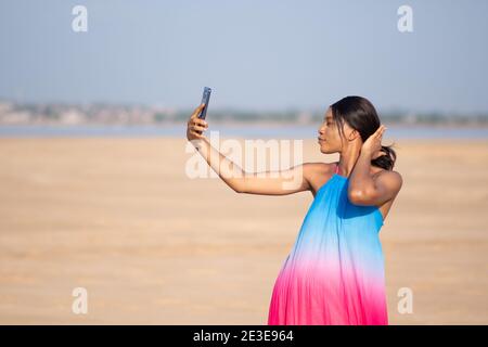 bella donna africana che prende selfie alla spiaggia Foto Stock