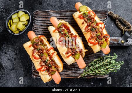 Hot dog con diversi condimenti. Sfondo di legno scuro. Vista dall'alto Foto Stock
