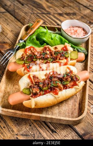 Hot dog con pancetta fritta, cipolla e cetrioli sottaceto. Sfondo in legno. Vista dall'alto Foto Stock