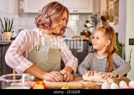 la bambina con le trecce indossa il grembiule, impara a cucinare, posa  vicino ai fornelli, prepara