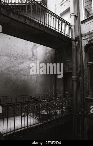 Immagine in scala di grigi di un vecchio edificio con pareti intemperie grunge e balconi con piante da casa Foto Stock