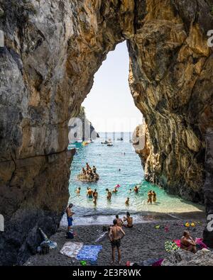 San Nicola Arcella, Calabria – Agosto 2020: Nuotatori che si godono la spiaggia sotto l'arco naturale dell'Arcomagno Foto Stock