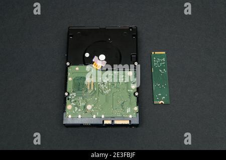 Confronto tra unità disco rigido HDD di grandi dimensioni e unità SSD NVME di piccole dimensioni DISCO M2 da sfondo grigio Foto Stock