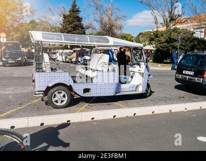 Lisbona, Portogallo - Feb 10, 2018: Tuk tuk vicino punto turistico a Lisbona dipinta in tegole tradizionali blu del portogallo Foto Stock