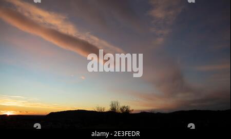 Cielo serale su orizzonte tramonto scuro. Alcuni uccelli come i punti che volano intorno agli alberi. Strane forme nuvolose. Foto Stock