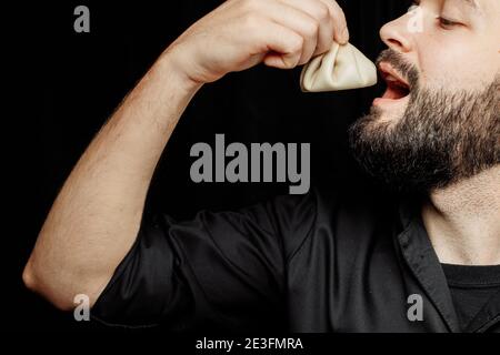 L'uomo bearded sta mangiando emotivamente khinkali. Il khinkali piatto georgiano nazionale. Concetto di pubblicità foto di khinkali Foto Stock