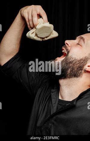 L'uomo bearded sta mangiando emotivamente khinkali. Il khinkali piatto georgiano nazionale. Concetto di pubblicità foto di khinkali Foto Stock