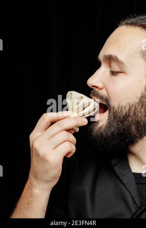 L'uomo bearded sta mangiando emotivamente khinkali. Il khinkali piatto georgiano nazionale. Concetto di pubblicità foto di khinkali Foto Stock