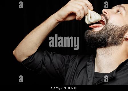 L'uomo bearded sta mangiando emotivamente khinkali. Il khinkali piatto georgiano nazionale. Concetto di pubblicità foto di khinkali Foto Stock