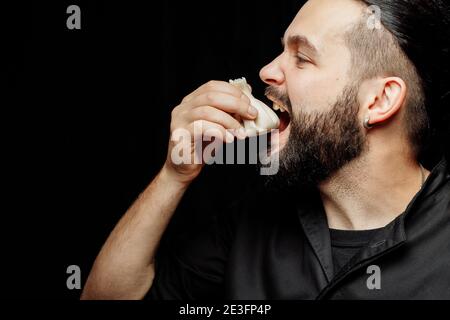 L'uomo bearded sta mangiando emotivamente khinkali. Il khinkali piatto georgiano nazionale. Concetto di pubblicità foto di khinkali Foto Stock