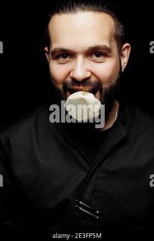 L'uomo bearded sta mangiando emotivamente khinkali. Il khinkali piatto georgiano nazionale. Concetto di pubblicità foto di khinkali Foto Stock